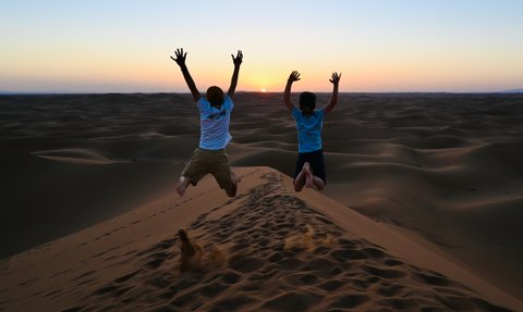 Kinder genießen den Sonnenuntergang in den Sanddünen der Sahara – Familienreise nach Marokko
