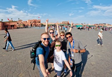 Reiseleiter und Familie posieren gemeinsam für ein Selfie auf Djemaa el Fna Platz in Marrakesch – Marokko Familienreise