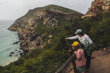 Mutter und Kind erkunden die Küstenlandschaft auf Robberg Island – Südafrika mit Kindern