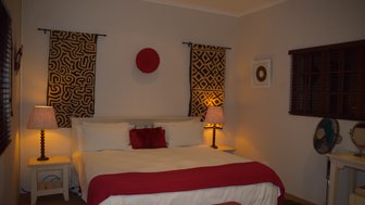 Ein gemütliches Schlafzimmer mit einem großen Bett, dekoriert mit roten und schwarzen Akzenten sowie stilvollen Wandbehängen.