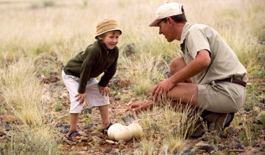 Ein Guide zeigt einem Kind ein großes Straußenei - Namibia mit Kindern