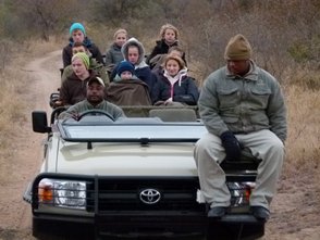 Offener Jeep mit neugieriger Reisegruppe auf Pirschfahrt durch die südafrikanische Wildnis – Südafrika Familienreise