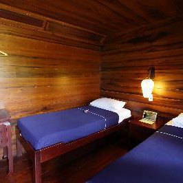 Ein gemütliches Zimmer mit zwei Einzelbetten, umgeben von warmen Holzvertäfelungen und sanfter Beleuchtung.