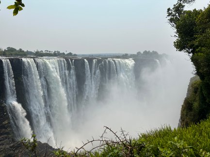 Die majestätischen Victoriafälle stürzen in einem beeindruckenden Wasserfall, umgeben von üppigem Grün und Nebel.