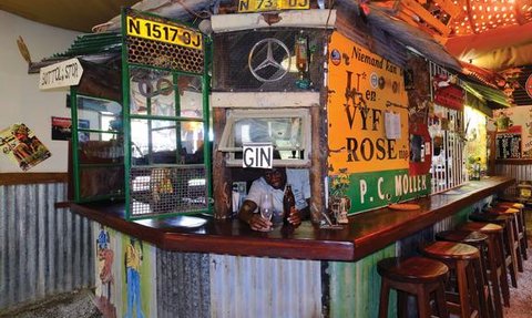 Ein rustikaler Barbereich mit bunten Wänden, einem Holztheke und einem freundlichen Barkeeper, der Getränke serviert.