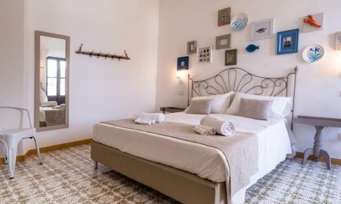 Ein helles Schlafzimmer mit einem großen Bett, dekoriert mit Kissen und einem Überwurf, strahlt Gemütlichkeit aus.