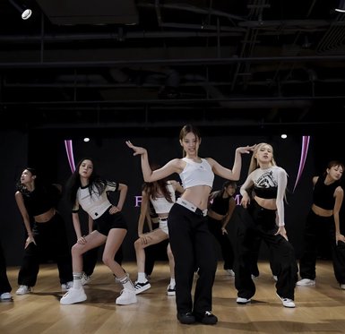Eine Gruppe von Tänzerinnen in sportlicher Kleidung führt synchronisierte Bewegungen in einem modernen Tanzstudio aus.