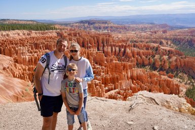 Eine Familie steht am Rand des Bryce Canyon, umgeben von beeindruckenden roten Felsformationen und einer weiten Landschaft.