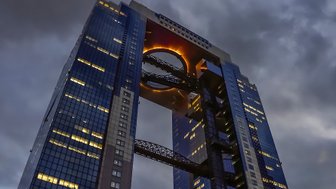 Ein beeindruckendes Hochhaus in Osaka, das durch seine einzigartige Architektur und die leuchtende Öffnung im oberen Bereich besticht.