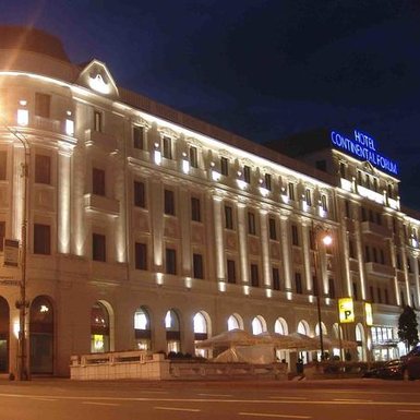 Das Hotel Continental Forum in Sibiu erstrahlt nachts in warmem Licht, das die elegante Architektur betont.