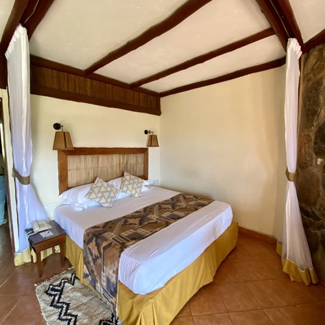 Ein gemütliches Zimmer mit einem großen Bett, dekoriert mit Kissen und einem kunstvollen Überwurf auf der Bettdecke.