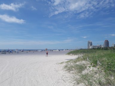 Ein sonniger Strand in Miami mit feinem, weißem Sand und einem klaren blauen Himmel, ideal für einen entspannten Tag.