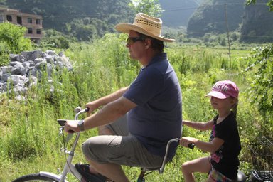 Vater und Kind entdecken gemeinsam die Landschaft von Yangshuo auf einer Fahrradtour – China Familienreise