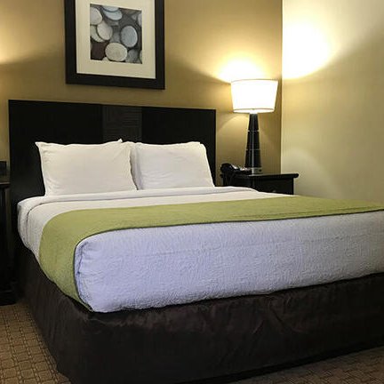 Ein gemütliches Hotelzimmer mit einem großen Bett, umgeben von warmen Farben und sanfter Beleuchtung.