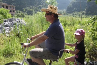Vater und Kind entdecken gemeinsam die Landschaft von Yangshuo auf einer Fahrradtour – China Familienreise