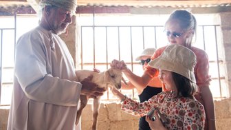 Kinder streicheln Ziege bei einem Farmbesuch im Oman – Oman mit Kindern
