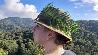 Teenager trägt einen braunen Hut mit grünen Farnblättern bei der Coral Hills-Wanderung in den Cameron Highlands - Malaysia Familienreise