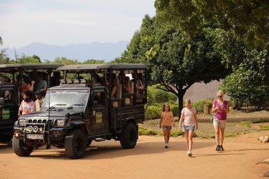 Eine Gruppe von Menschen steigt aus einem Jeep aus, während Kinder auf dem Weg zu einem Abenteuer sind.