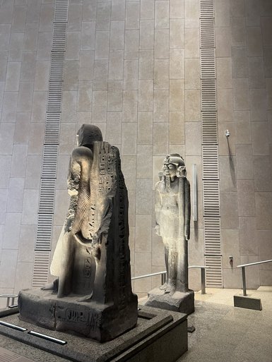 Zwei monumentale ägyptische Statuen stehen in einem modernen Museum, die eine tiefere Verbindung zur Vergangenheit darstellen.