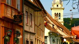Eine belebte Straße mit bunten Häusern, wo ein Mann und eine Frau entspannt spazieren gehen, umgeben von historischen Gebäuden.