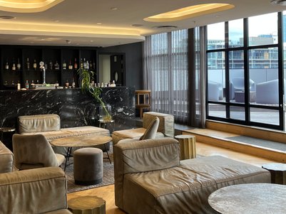 Ein eleganter Lobbybereich mit bequemen, hellen Sofas und einem stilvollen Tisch, umgeben von großen Fenstern.