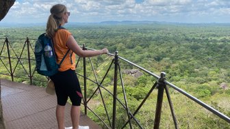 Frau blickt vom Sigiriya-Felsen auf die grüne Landschaft und den weiten Horizont – Sri Lanka Familienreise