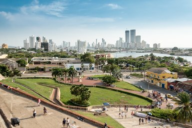 Ein Blick auf die moderne Skyline von Cartagena, umgeben von üppigem Grün und lebhaften Straßen mit Menschen und Fahrzeugen.