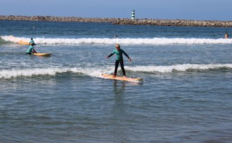 Ein junger Surfer balanciert geschickt auf seinem Surfbrett in den sanften Wellen des Meeres.