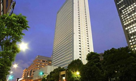 Ein hochmodernes Hotelgebäude erhebt sich majestätisch gegen den Abendhimmel, umgeben von urbaner Landschaft und Bäumen.
