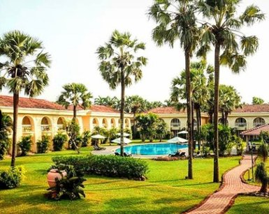 Ein luxuriöses Resort in Goa mit einem einladenden Pool, umgeben von üppigem Grün und hohen Palmen.