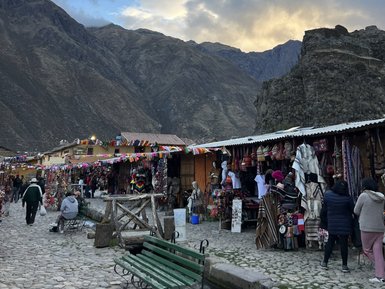 Bunte Stände mit handgefertigten Waren säumen die gepflasterte Straße in Ollantaytambo, umgeben von majestätischen Bergen.