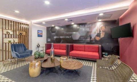 Ein modernes Lounge-Interieur mit roten Sofas, einem blauen Sessel und stilvollen Holzelementen, das eine entspannte Atmosphäre schafft.