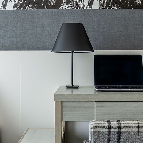 Ein modernes Hotelzimmer mit einem gemütlichen Bett, einem Schreibtisch und einem Laptop, ideal für Geschäftsreisende.