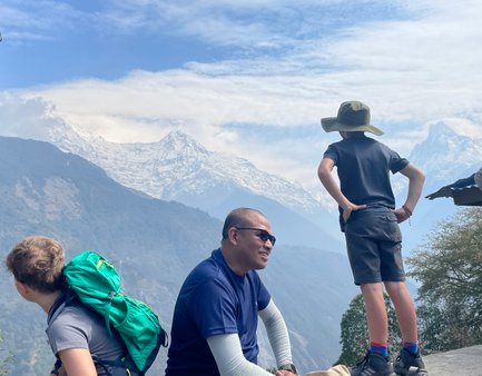 Ein Junge mit einem Hut steht nachdenklich auf einem Felsen und blickt auf die majestätischen schneebedeckten Berge.
