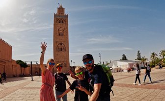 Familie hält einen Moment mit einem Selfie vor der Koutoubia-Moschee fest – Marokko Familienreise