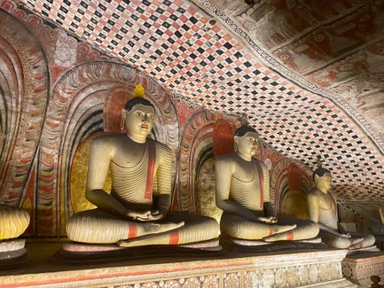 Reihe von Buddha-Statuen im Inneren des Dambulla-Höhlentempels – Sri Lanka mit Kindern