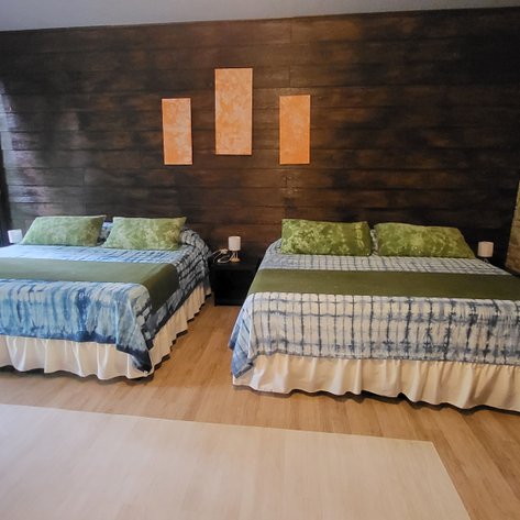 Zwei komfortable Betten mit bunten Bettwäsche und Kissen in einem gemütlichen Zimmer mit Holzverkleidung.