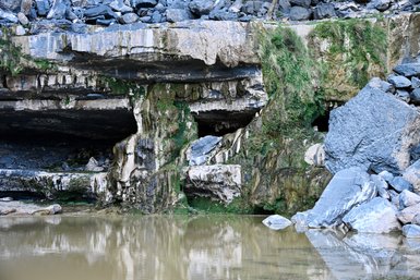 Szenerie aus schroffen Felsen und einem kleinen See am Jebel Shams – Oman Reise mit Kindern