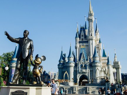Eine bronzene Statue von Walt Disney und Mickey Mouse steht vor dem majestätischen Schloss im Magic Kingdom.