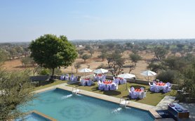 Ein Blick auf den Pool des Hotels Mandawa Haveli, umgeben von eleganten Tischen und Sonnenschirmen im Freien.