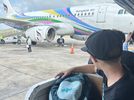 Kind mit Rucksack wartet auf Boarding ins Flugzeug - Thailand mit Kindern