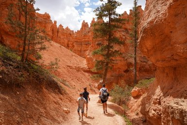Eine Familie wandert auf einem schmalen Pfad durch die beeindruckenden roten Felsen des Bryce Canyon Nationalparks.