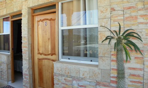Die Eingangstür aus Holz mit der Nummer 8 ist von einer bunten Steinmauer umgeben und hat ein modernes, einladendes Design.