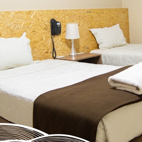 Zwei Einzelbetten mit weißen Bettdecken und Kissen, ergänzt durch einen Nachttisch mit einer Lampe und einem Telefon.