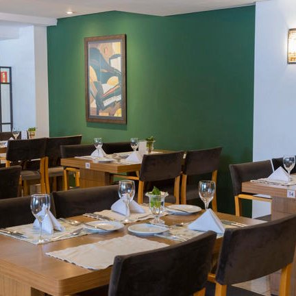 Ein stilvolles Restaurant-Interieur mit eleganten Holztischen und schön dekorierten Teller-Setups in sanften Farben.