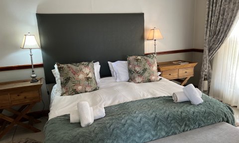 Das gemütliche Schlafzimmer des Oudshoorn Berluda Farm House mit eleganter Einrichtung und Planzenkissen