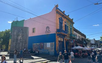 Bunte Gebäude in Buenos Aires, umgeben von Menschen, die die lebhafte Atmosphäre des Stadtteils genießen.