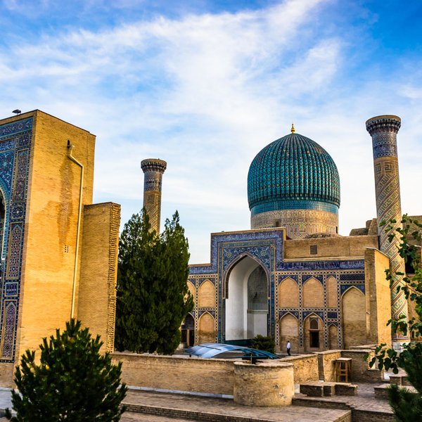 Die beeindruckende Architektur von Samarkand zeigt eine große Kuppel und kunstvoll verzierte Wände unter einem blauen Himmel.