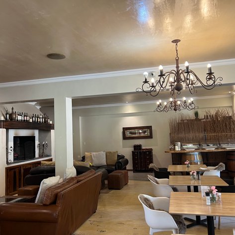 Ein einladendes Wohnzimmer mit bequemen Ledersofas, einem eleganten Kronleuchter und einer stilvollen Bar im Hintergrund.