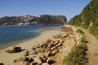 Ruhiger Strandabschnitt mit sanften Wellen und markanten Felsen in Knysna – Garden Route Reise mit Kindern